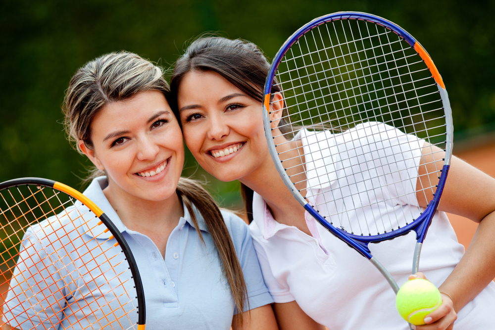 Beautiful female tennis players holding rackets and smiling