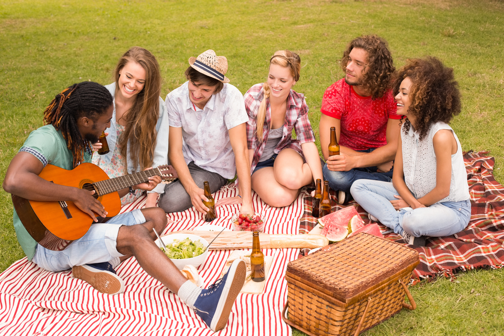 Happy friends in the park having picnic on a sunny day