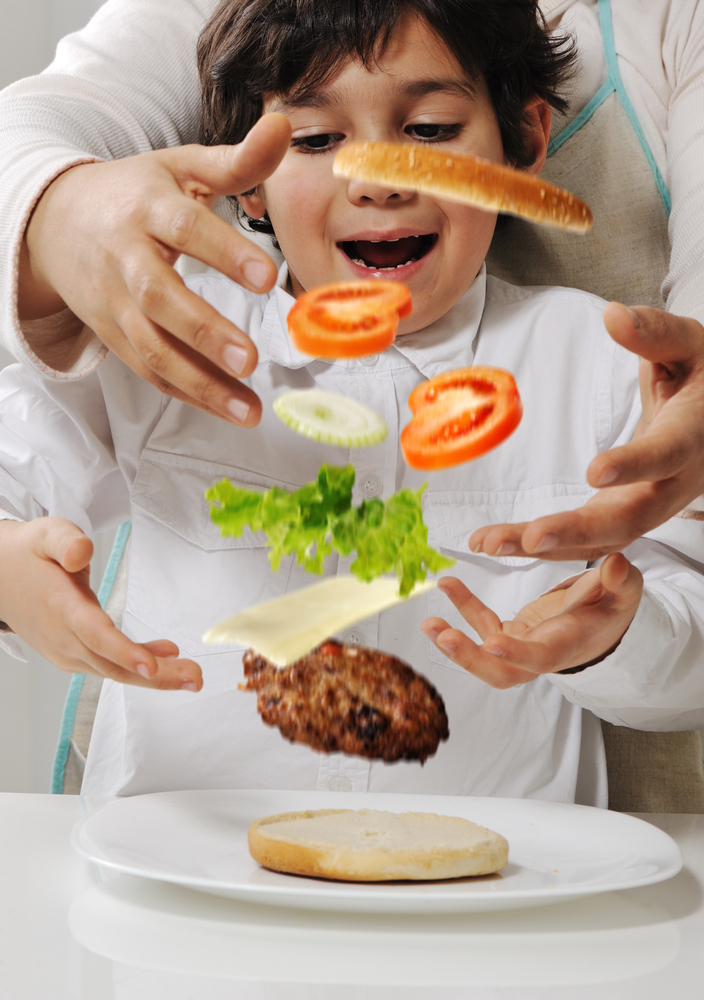 Mother and son making burger at kitchen