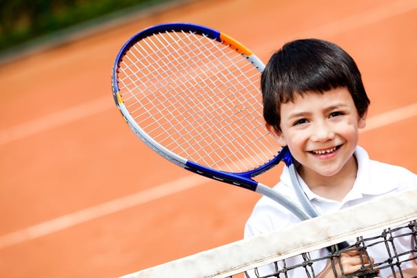 Young boy playing tennis at a clay court.jpeg